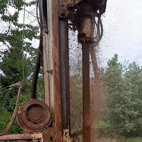 Souprava na louce, z vrtu teče kalná hnědá voda